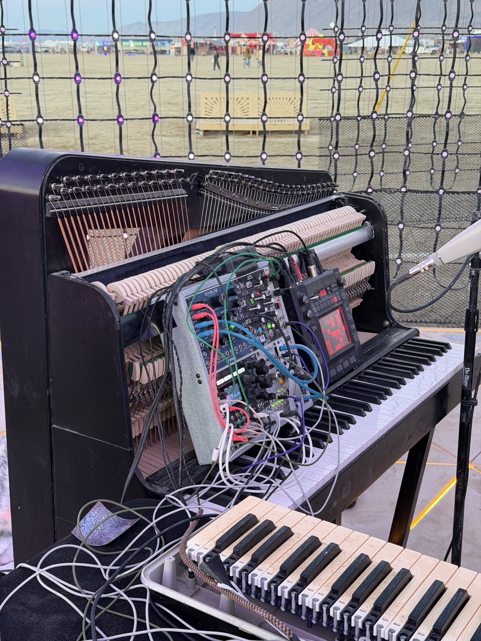 An upright piano opened up with synth modules built into it, a keyboard in front
