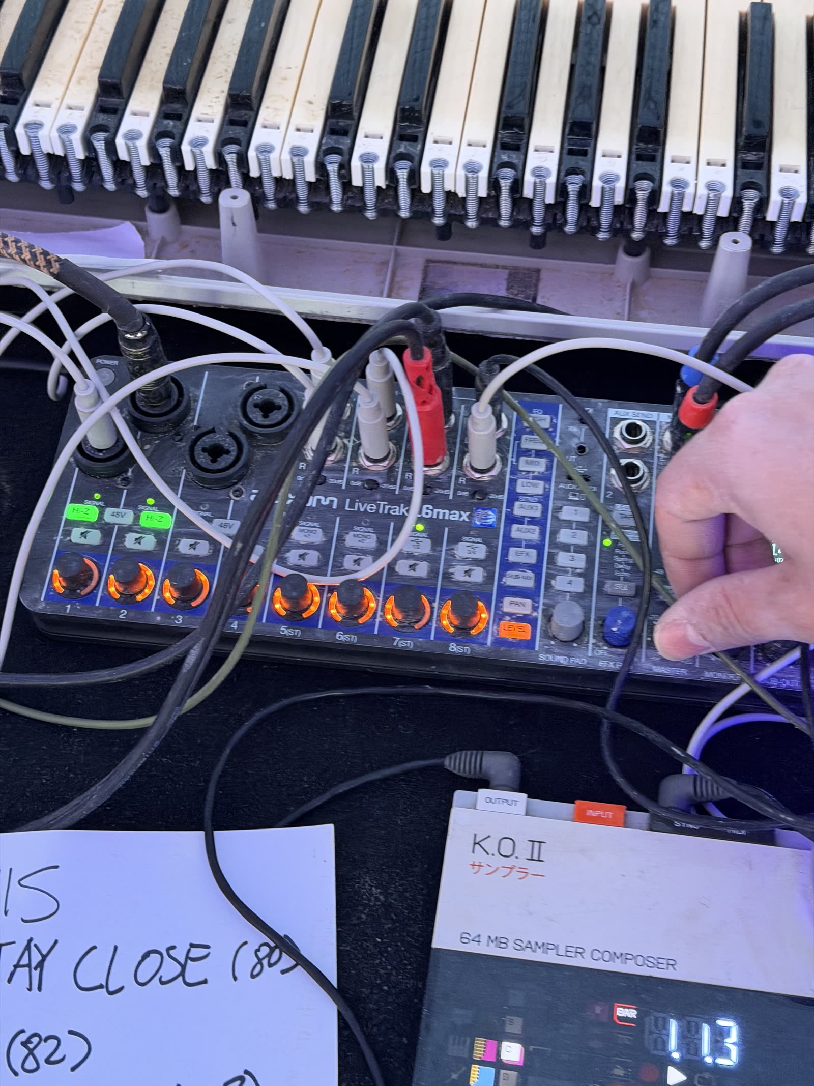 A handwritten setlist next to a sampler and a keyboard