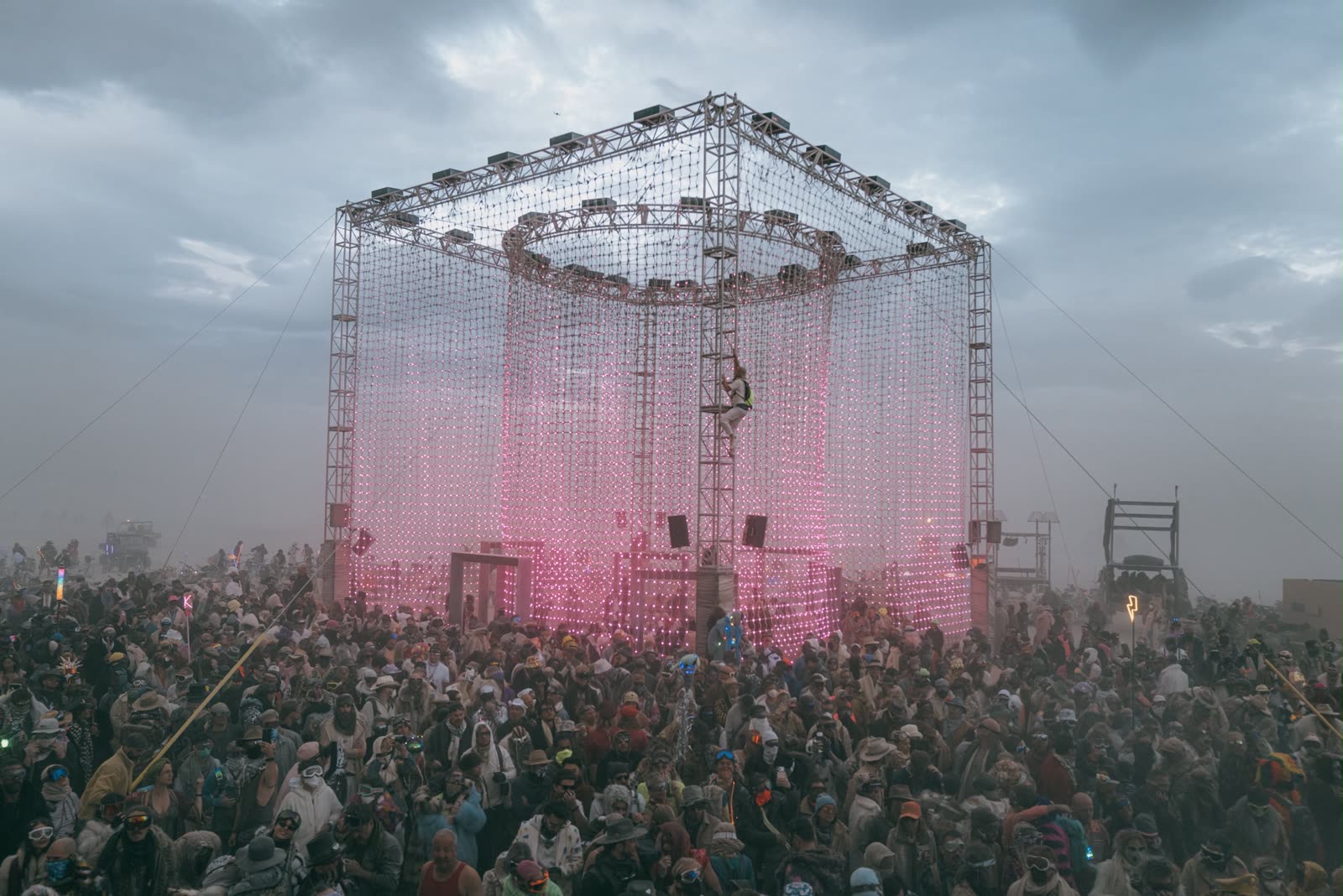 The cube lit pink in the dust, the crowd around it